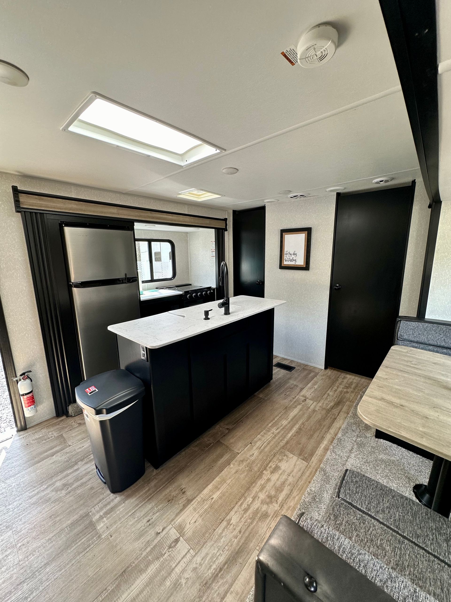 A kitchen in a rv with a large island and a refrigerator.