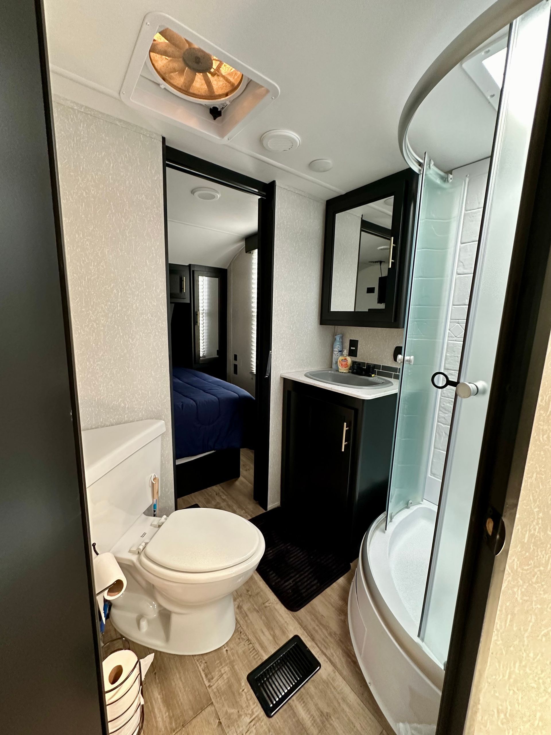 A bathroom with a toilet , sink and shower.