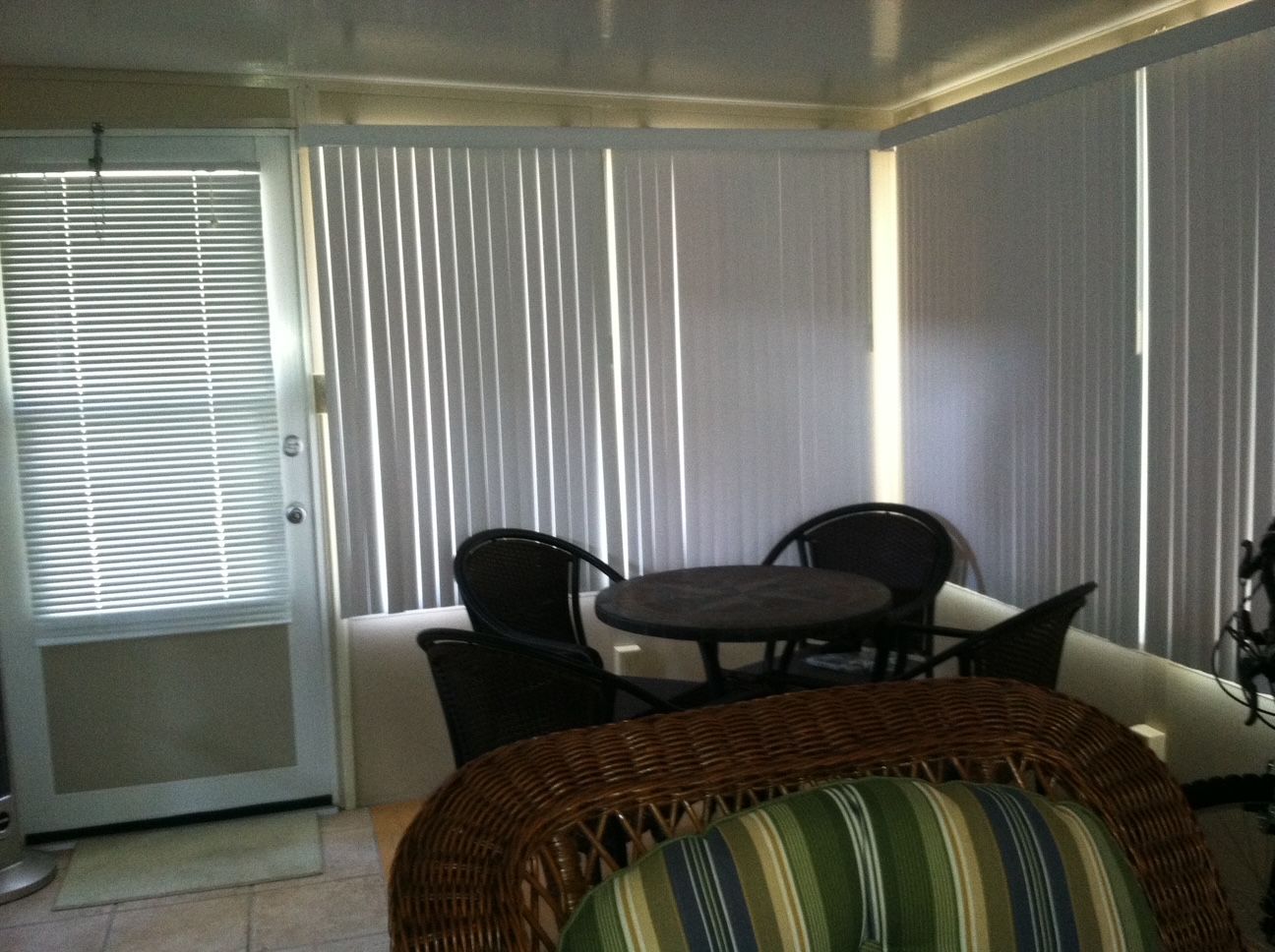 Sunroom with wicker chairs and round table beside vertical blinds and a glass door