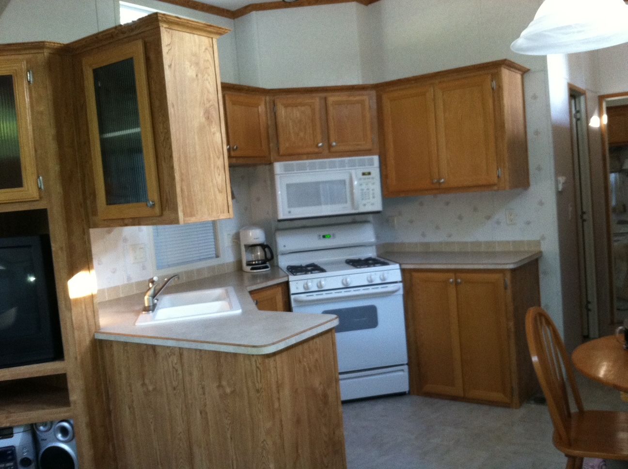 Small kitchen with wooden cabinets, white appliances, and a light countertop in a home.