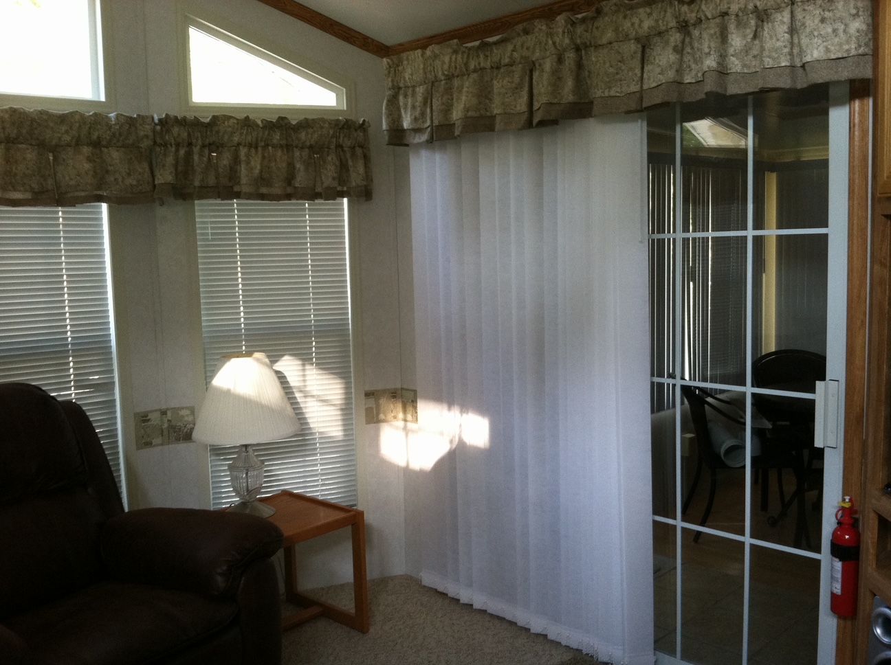 Living room with blinds, lamp, sheer curtain, and sliding glass door