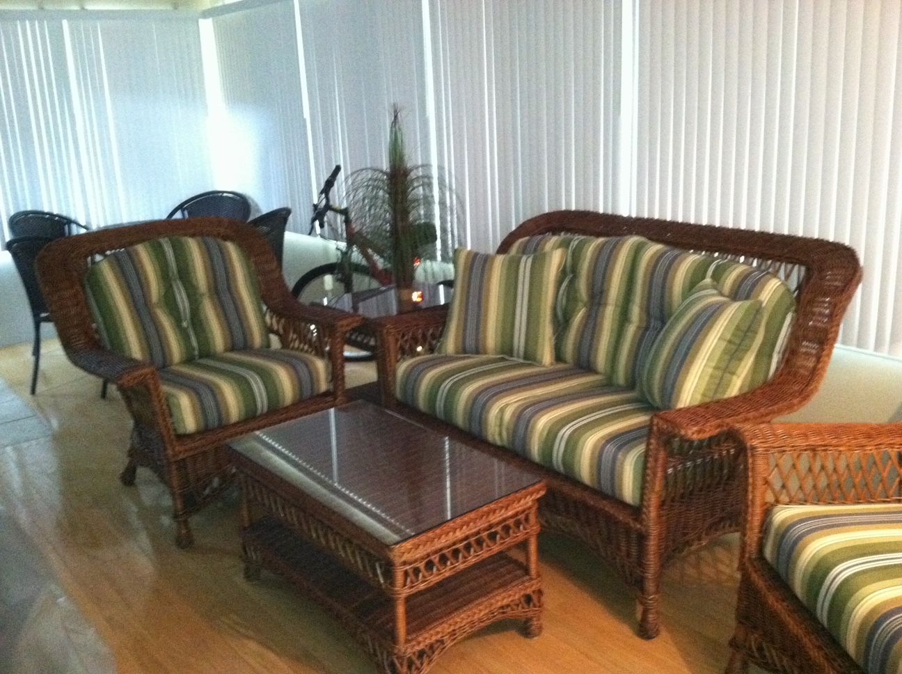 Living room with wicker sofa set, striped cushions, and glass coffee table