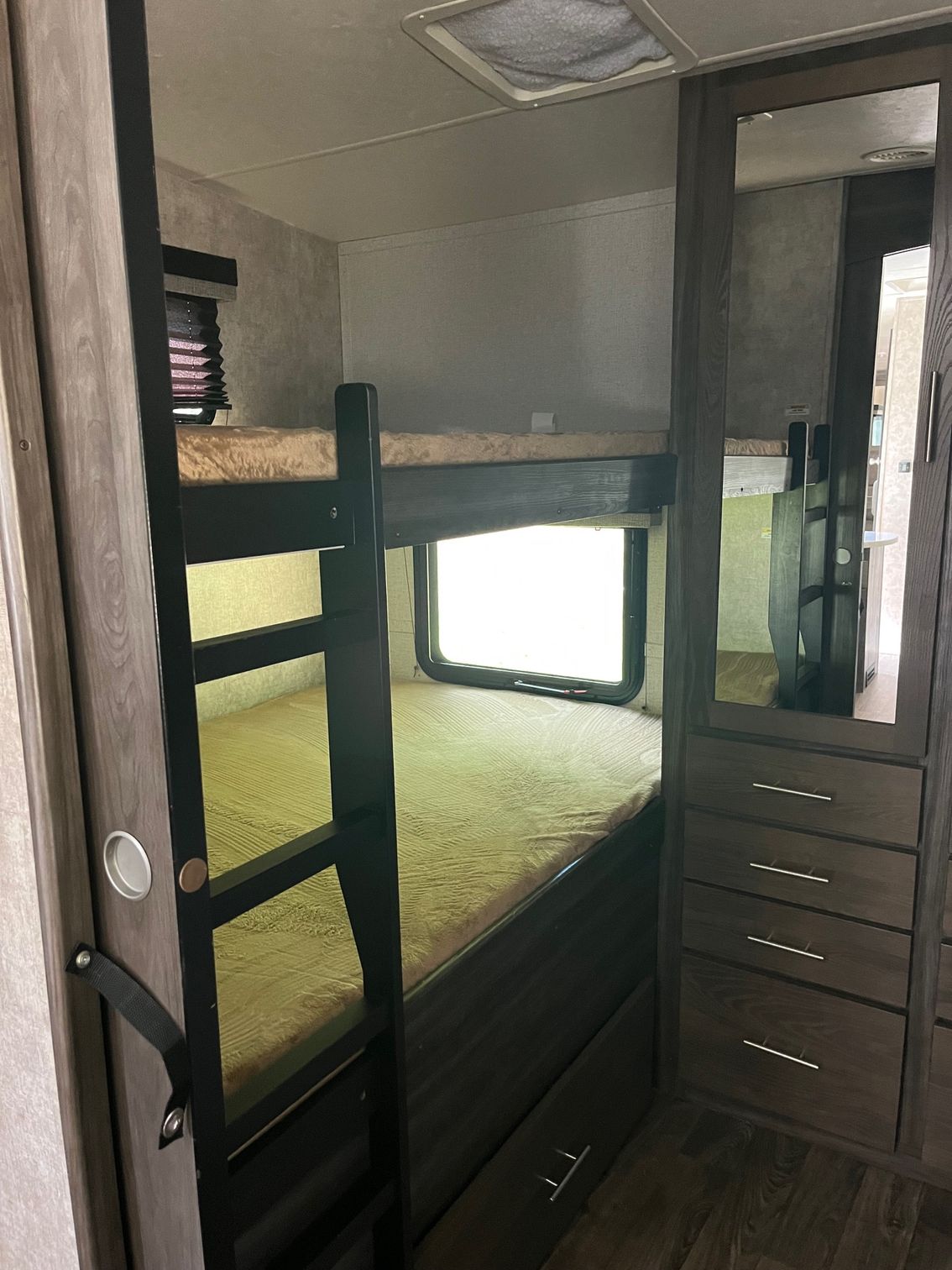 Small bedroom with bunk bed, built-in drawers, and a mirrored wardrobe.