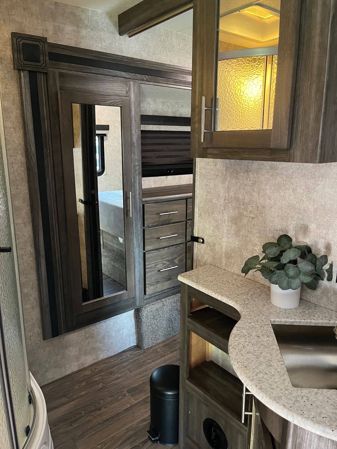 RV interior with mirrored closet, wood cabinets, countertop, and warm window light