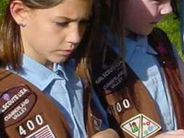 Girl Scouts in uniform; Cumberland Valley patch, brown vests, blue shirts, looking down.