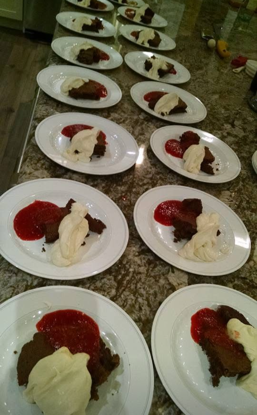 Rows of plated dessert portions with red sauce and white cream on a speckled countertop