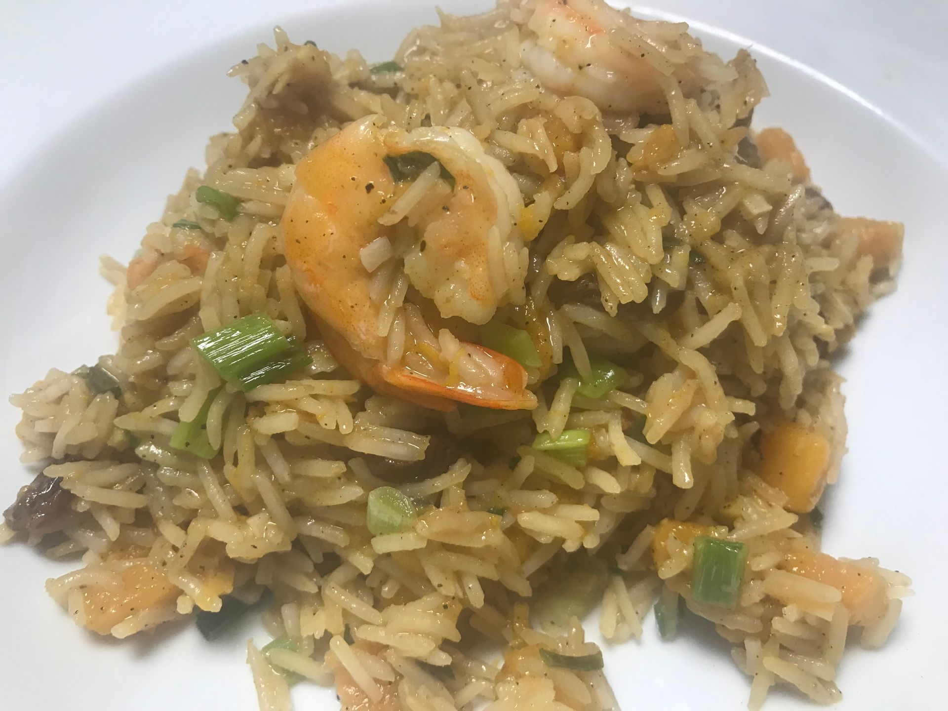Plate of fried rice with vegetables and shrimp on a white dish