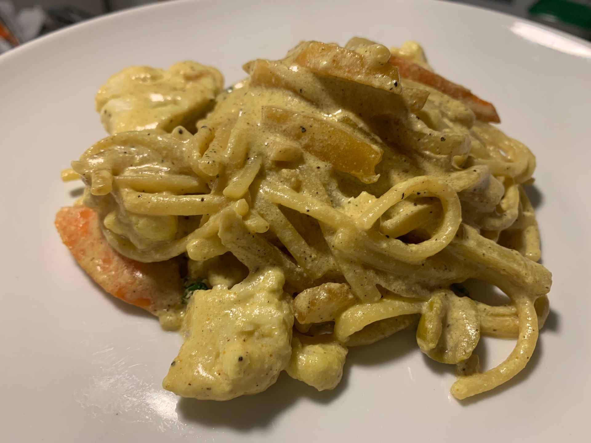 Creamy pasta with shrimp and vegetables on a white plate