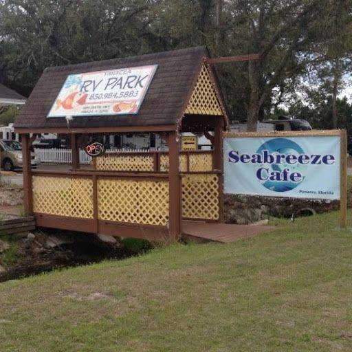 RV Park kiosk beside a Seabreeze Cafe sign on a grassy roadside area