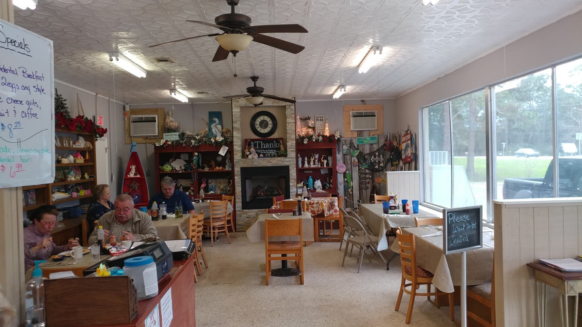 Bright living room with cluttered decor, ceiling fan, TV, chairs, and large sliding glass doors.