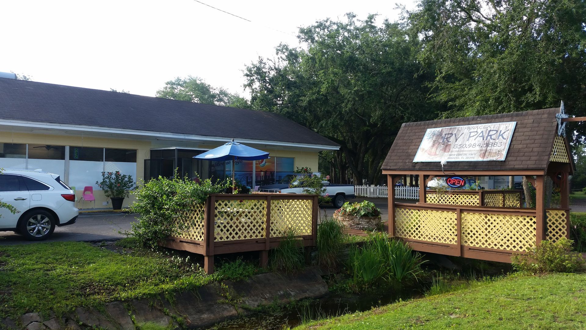 Two small wooden deck structures in a grassy yard beside a house and parked car