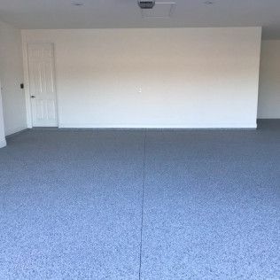 An empty garage with a gray floor and white walls.