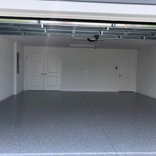 A large empty garage with a gray floor and white walls.