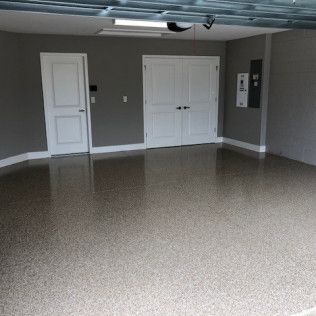An empty garage with a concrete floor and white doors.