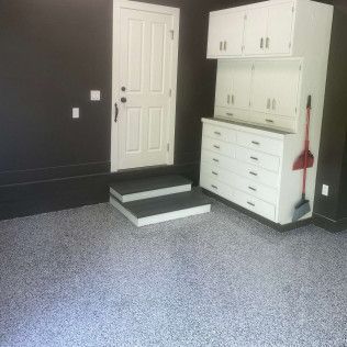 A garage with stairs leading up to a door and cabinets