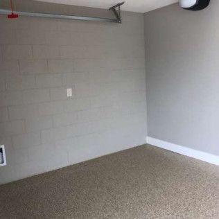 An empty garage with a brick wall and a carpeted floor.
