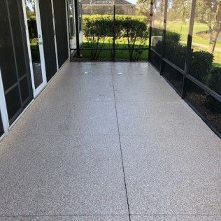A screened in porch with a concrete floor and sliding glass doors.