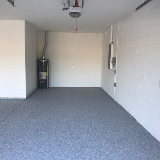 An empty garage with a gray carpeted floor and white walls.