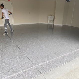 A man is cleaning a garage floor with a broom.