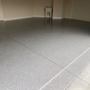 A gray concrete floor in a garage with a sink in the background.