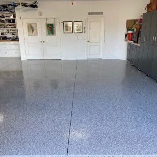 A garage with a gray floor and white cabinets.