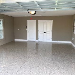 An empty garage with a garage door open and a light on the ceiling.