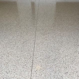 Close-up of a light gray speckled tile floor with a narrow seam running vertically.