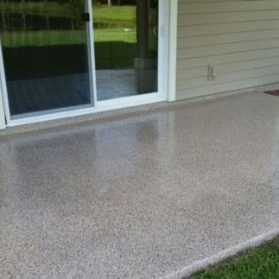 A patio with a sliding glass door and a concrete floor.