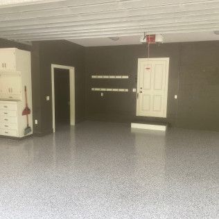 An empty garage with a gray floor and a white door.