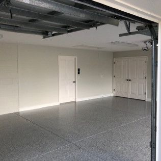 An empty garage with a garage door open and a gray floor.