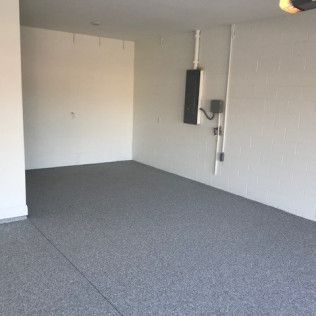 An empty garage with a gray floor and white walls.