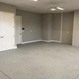 A large empty room with a ceiling fan and a gray carpet.
