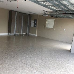 A large empty garage with a concrete floor and cabinets.