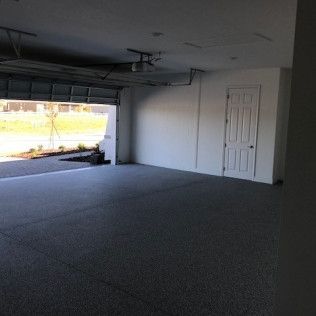 An empty garage with a garage door open and a ceiling fan.