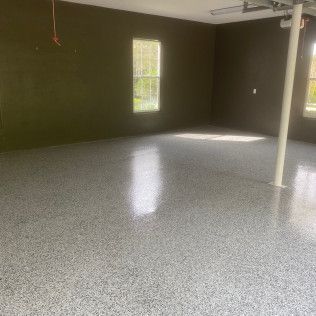 An empty garage with a gray floor and black walls.