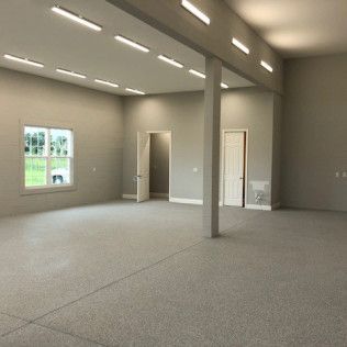 A large empty room with a carpeted floor and a window.