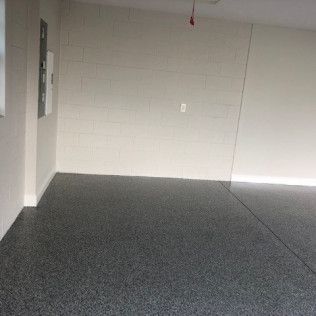 An empty garage with a black floor and white walls.