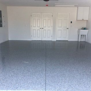A large empty garage with a gray floor and white doors.