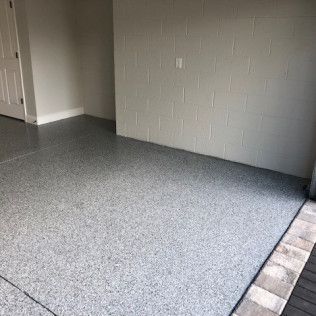 A room with a gray floor and a white brick wall.