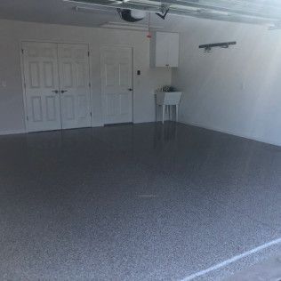An empty garage with a gray floor and white doors.