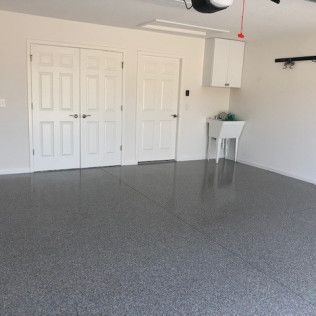 An empty garage with a sink and a garage door open.