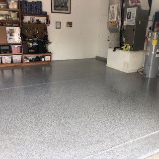 A garage with a gray floor and a refrigerator.