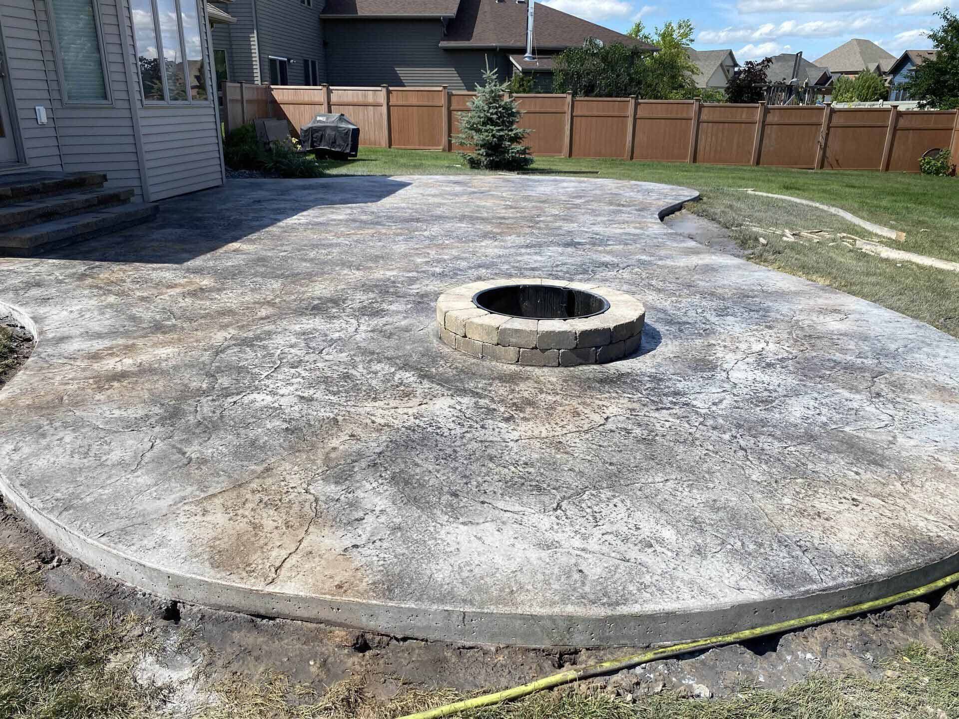 A concrete patio with a fire pit in the middle of it.