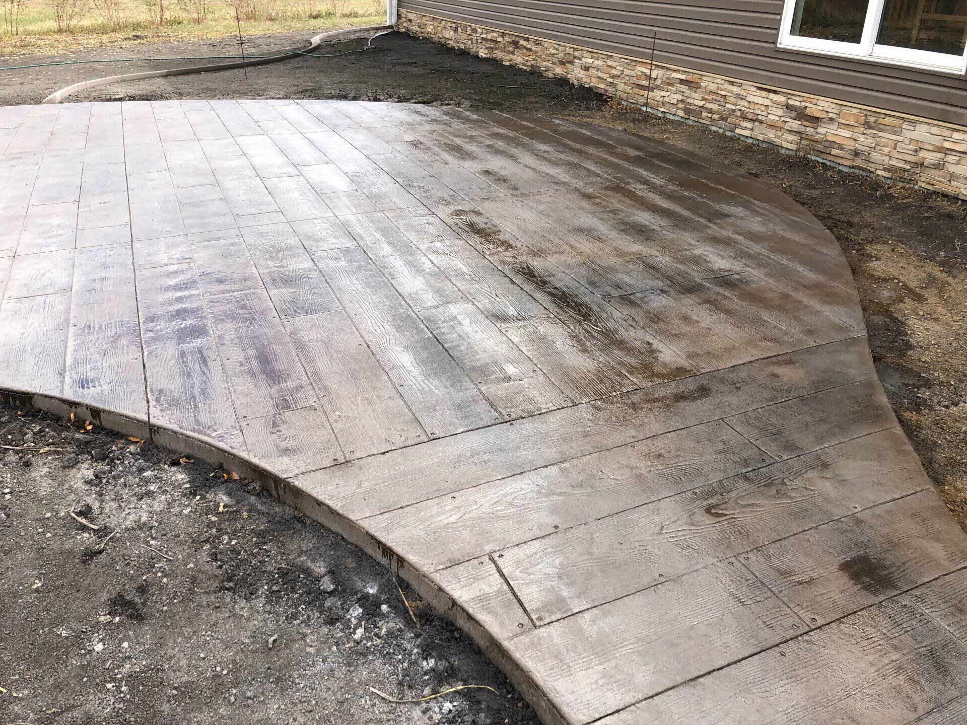 A concrete walkway that looks like wood is being built in front of a house.