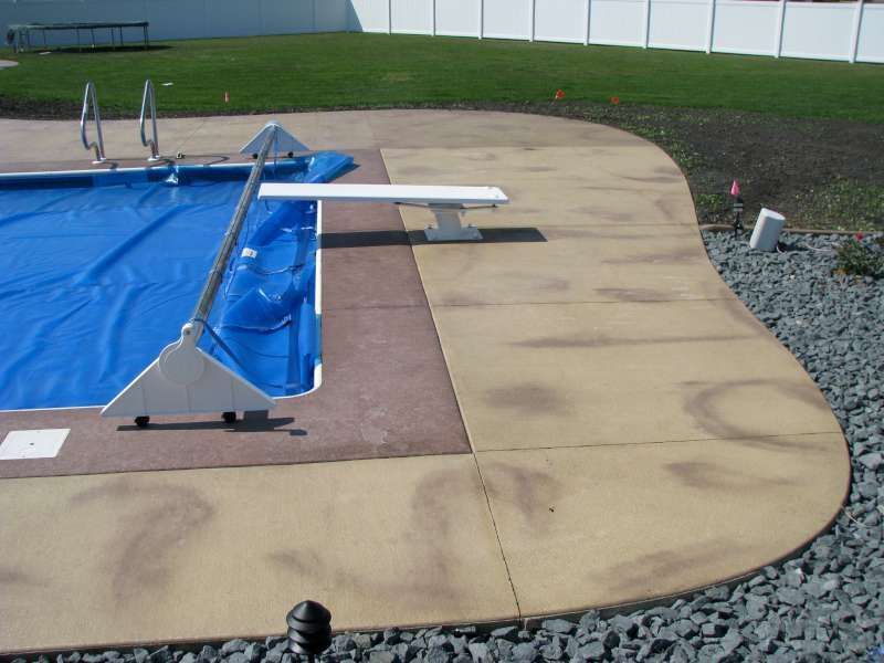 A swimming pool with a blue cover and a diving board