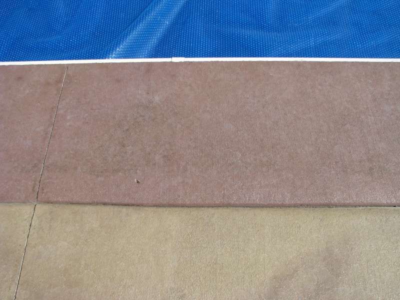 A swimming pool with a blue cover and a concrete border.