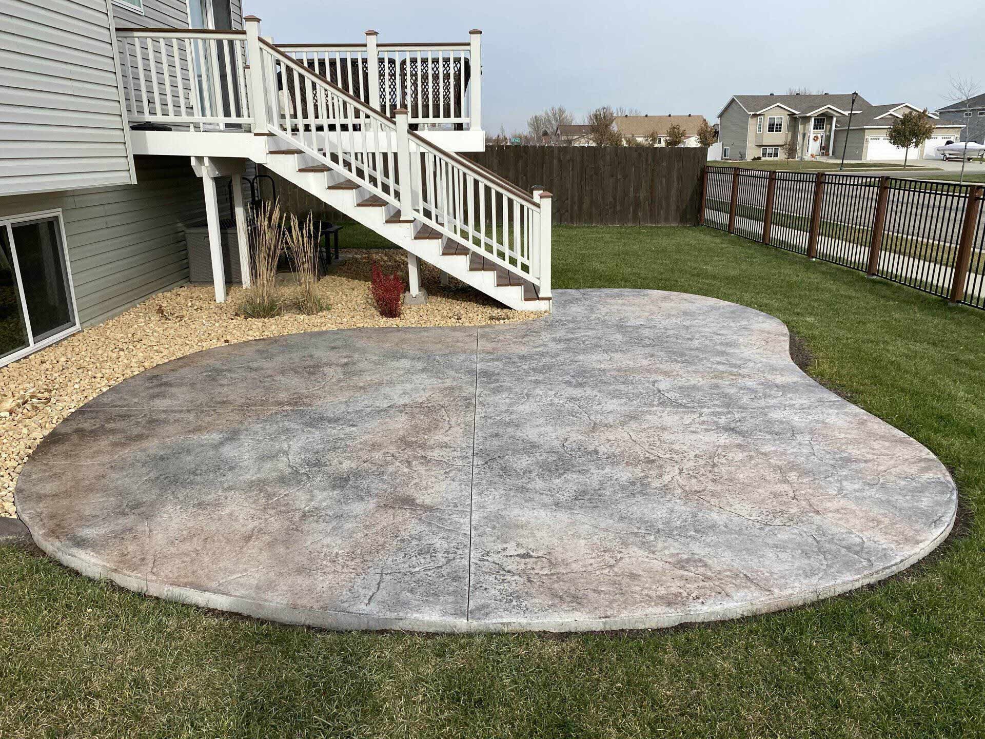 A patio with a deck and stairs in the backyard of a house.