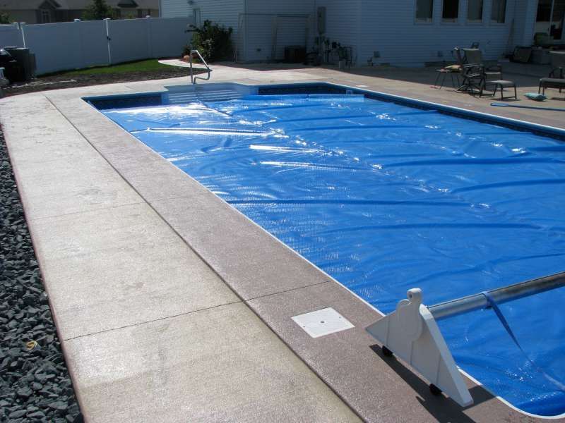 A large swimming pool with a blue cover on it