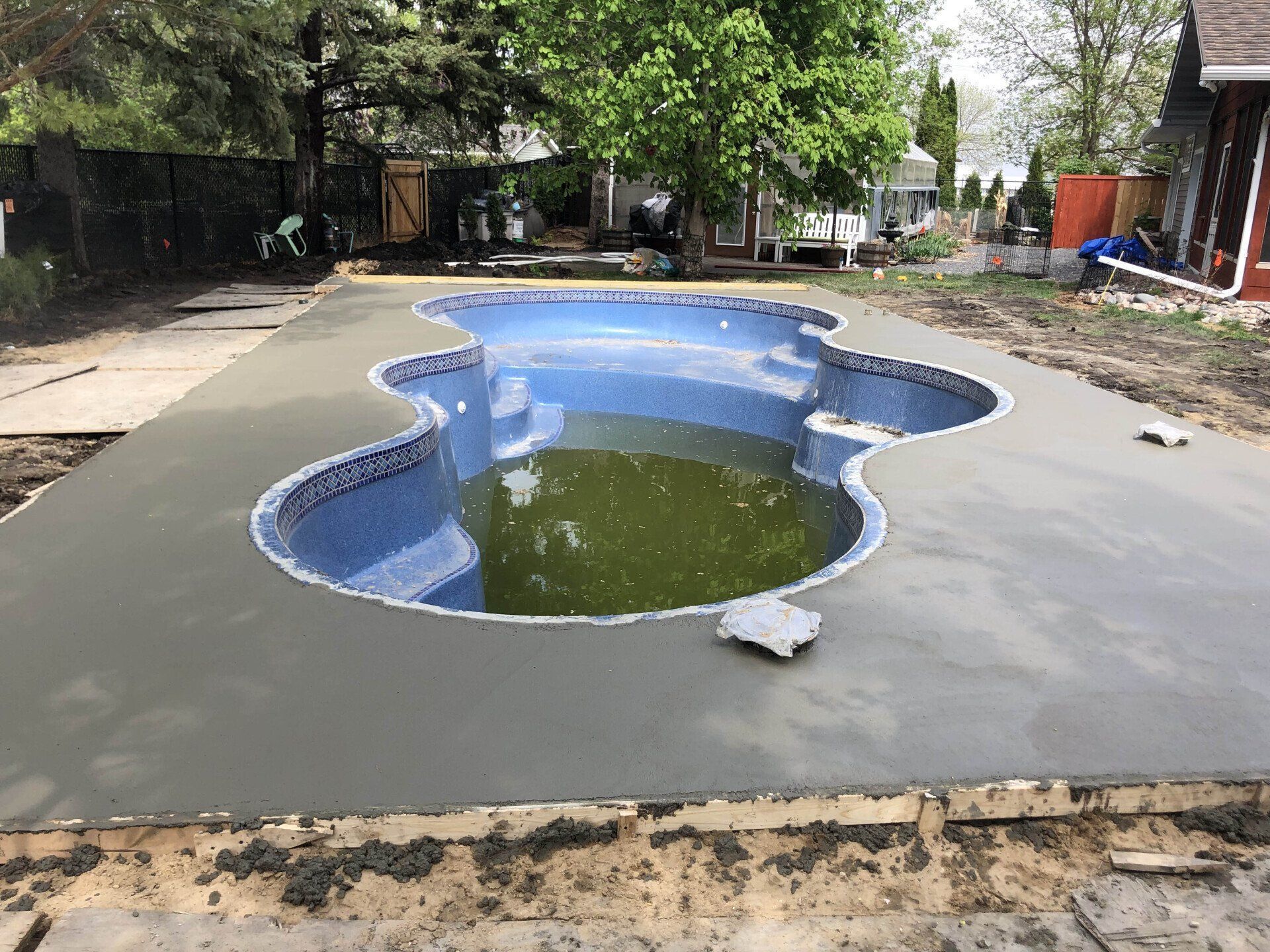 A large swimming pool is being built in a backyard.