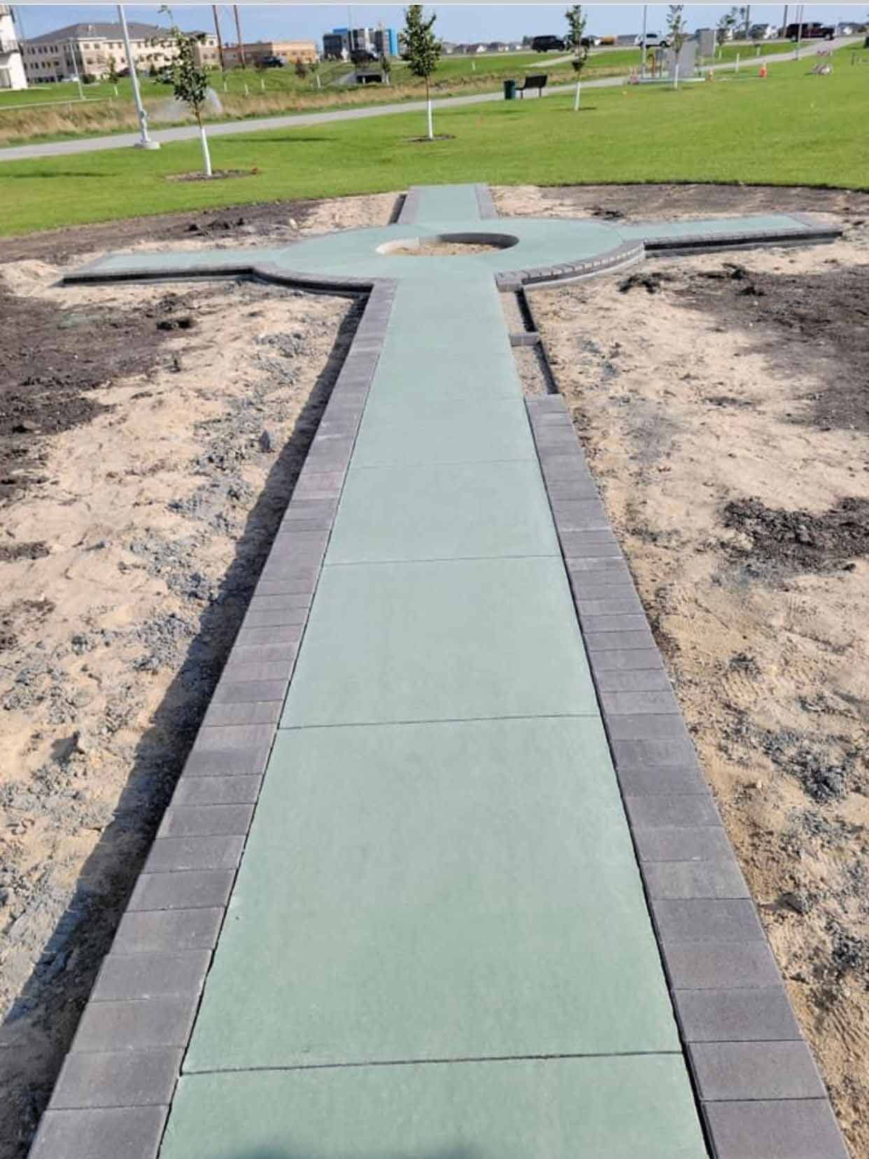 A walkway is being built in a park with a cross in the middle.